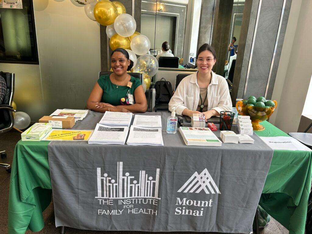 Two Institute staff members sitting at a table at the 17th Street health fair on August 5, 2026.