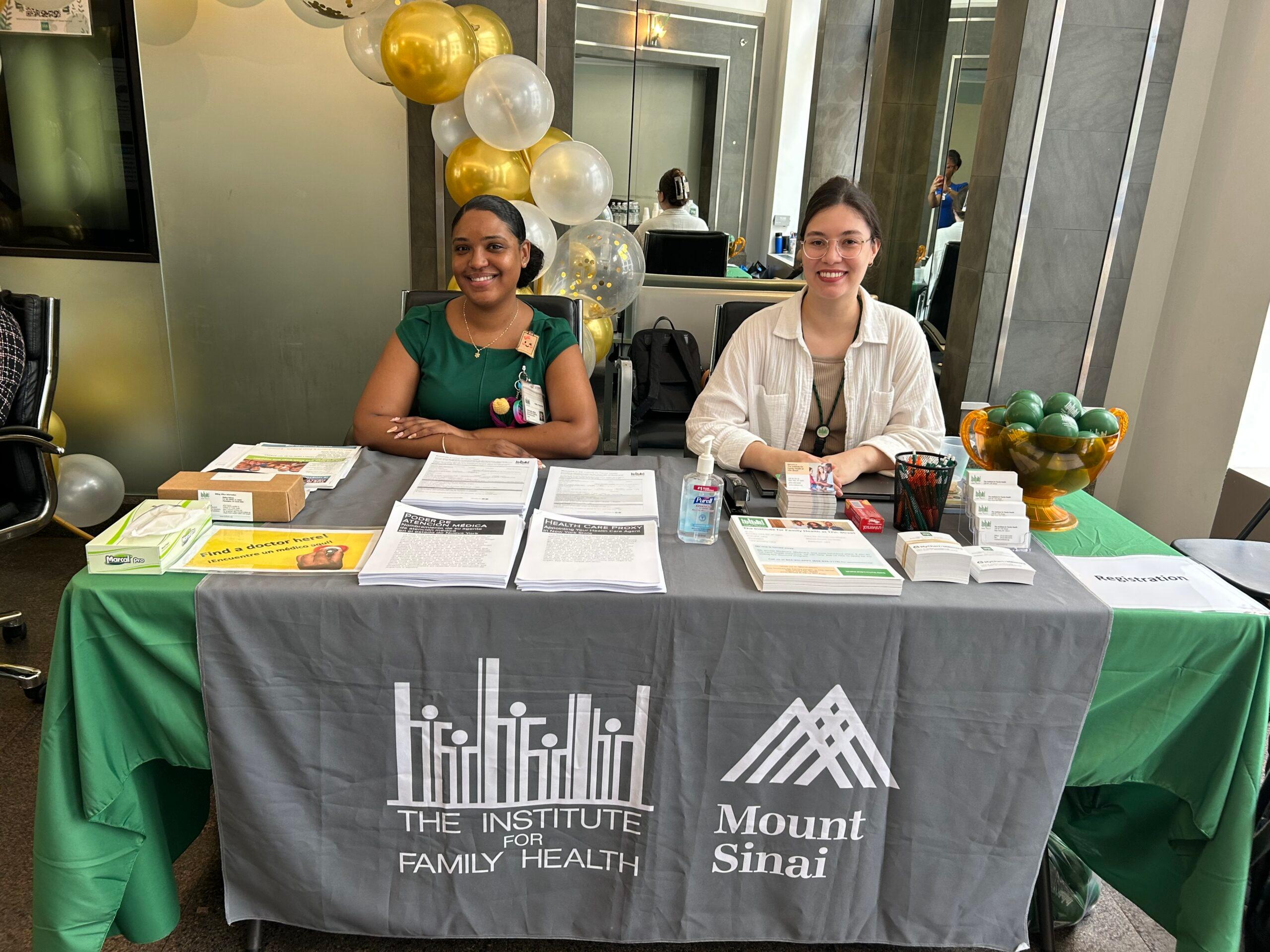 Two Institute staff members sitting at a table at the 17th Street health fair on August 5, 2026.